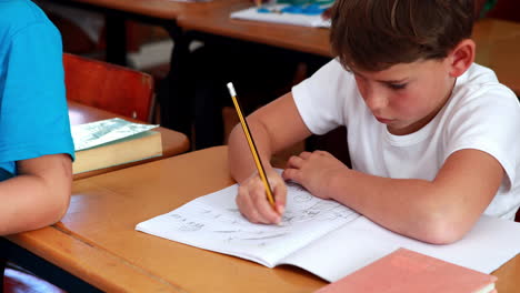 Kleiner-Junge-Zeichnet-Im-Klassenzimmer-Im-Notizblock