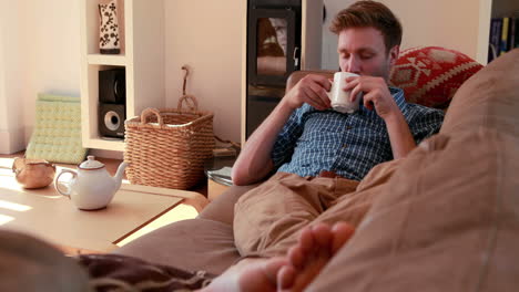 Handsome-young-man-relaxing-on-his-couch-with-a-hot-drink