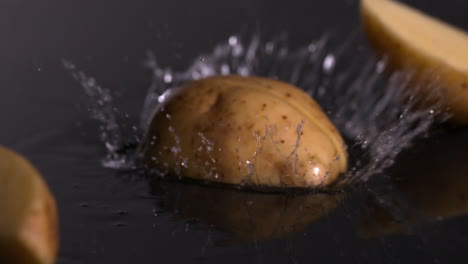 Kartoffelstücke-Fallen-Auf-Nassen-Schwarzen-Hintergrund
