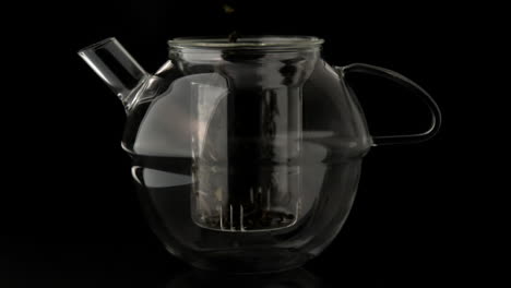 Loose-tea-pouring-into-glass-teapot