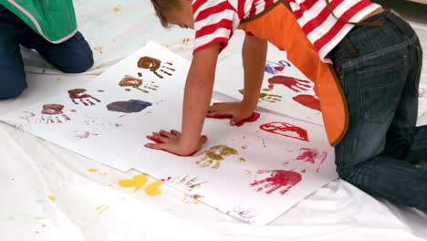 Cute-little-boys-painting-lying-on-paper-in-classroom