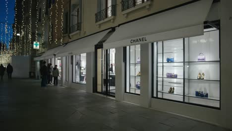 Tienda-Chanel-Con-Exhibidores-Iluminados-En-Una-Calle-Nocturna-En-Venecia,-Italia