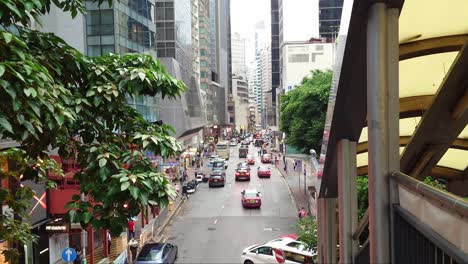 Rear-view-of-vehicles-passing-through-Central---Queen's-Road-during-summer-evening-in-Hong-Kong,-China