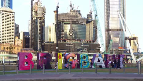 The-iconic-landmark,-the-Brisbane-City-sign,-stands-against-the-backdrop-of-the-under-construction-Queen's-Wharf-and-Neville-Bonner-Bridge