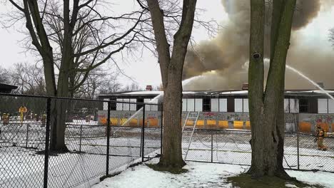 Los-Bomberos-Extinguen-Un-Incendio-En-Un-Edificio-De-Una-Escuela-De-Jardín-De-Infantes-Abandonado-Mientras-Una-Nube-De-Humo-Negro-Se-Eleva-En-El-Aire.