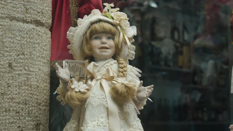 Primer-Plano-De-Una-Muñeca-Vintage-Con-Un-Elaborado-Vestido-De-Encaje,-Exhibida-En-Un-Escaparate-En-Venecia,-Italia