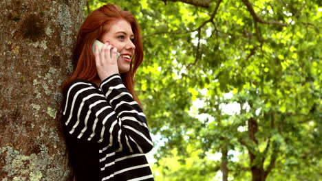 Pretty-redhead-talking-on-the-phone-in-the-park