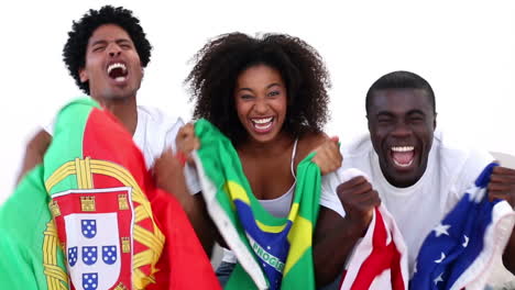 Football-fans-in-white-sitting-on-couch-holding-flags