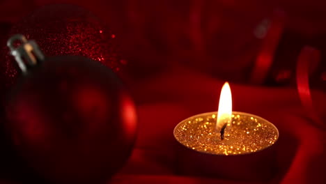 Gold-glitter-candle-flickering-beside-bauble