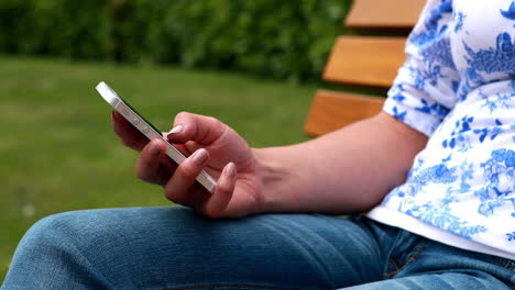 Woman-sitting-on-park-bench-texting