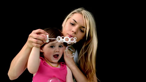 Cute-little-girl-blowing-bubbles-with-mother