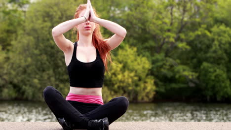 Calm-redhead-doing-yoga-by-a-lake-