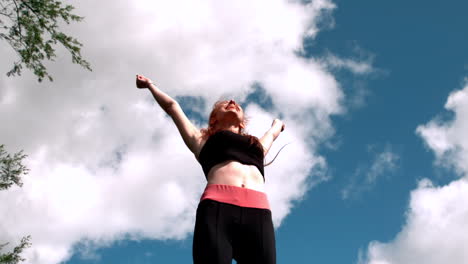 Fit-redhead-cheering-under-blue-sky