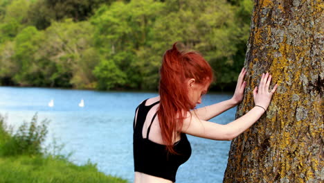 Fit-redhead-warming-up-against-a-tree