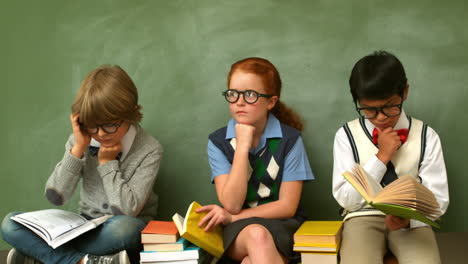 Focused-pupils-sitting-in-classroom-reading-books