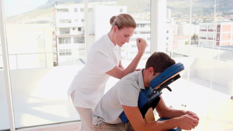 -Terapeuta-Femenina-Masajeando-A-Un-Hombre-Sentado-En-Una-Silla-De-Masaje