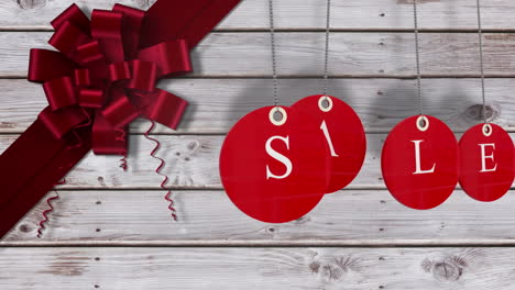 Red-sale-tags-hanging-against-wood-with-festive-bow