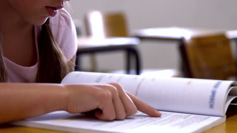 Schoolgirl-reading-at-desk-in-school