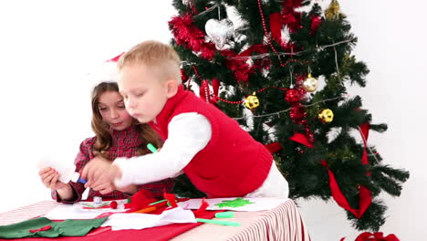 Cute-siblings-making-art-by-the-christmas-tree