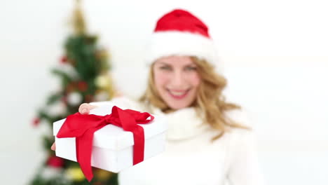 Festive-blonde-smiling-at-camera-offering-gift
