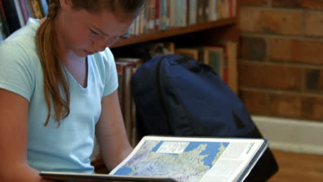 Cute-pupil-reading-on-library-floor