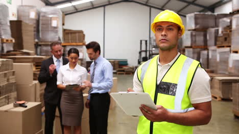 Warehouse-managers-talking-while-worker-uses-tablet-pc