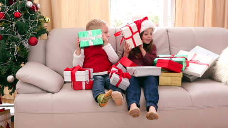 Cute-siblings-sitting-on-couch-with-lots-of-christmas-gifts