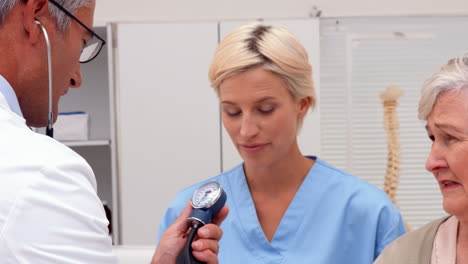 Doctor-taking-blood-pressure-of-patient-with-nurse