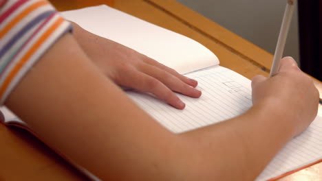 Schoolchild-writing-in-notepad-at-school