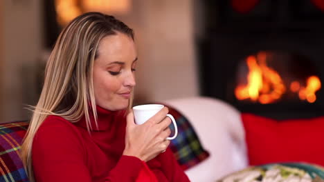 Pretty-blonde-enjoying-a-hot-drink-on-the-couch