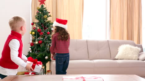 Cute-siblings-putting-presents-under-the-christmas-tree