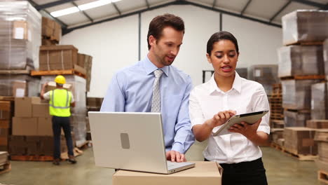 Warehouse-managers-looking-at-tablet-pc-and-laptop