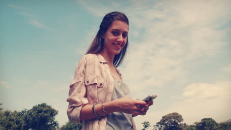 Pretty-brunette-texting-in-the-park