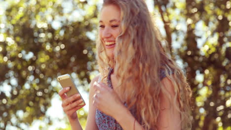 In-high-quality-4k-format-pretty-blonde-using-phone-in-the-park-