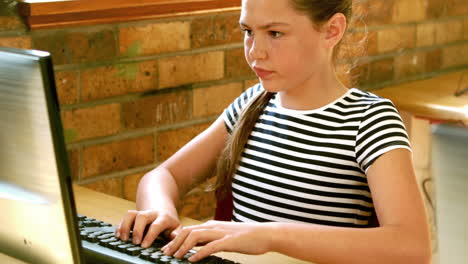 Cute-pupil-looking-at-laptop-in-classroom