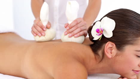 Woman-enjoying-a-herbal-compress-massage