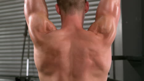 Rear-view-of-a-fit-man-lifting-dumbbells