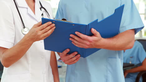 Two-doctors-holding-clipboard-in-medical-office