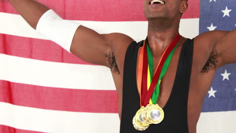 Glücklicher-Sportler-Mit-Medaillen,-Die-Die-Amerikanische-Flagge-Halten-Und-Jubeln