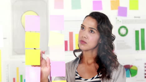 Lächelnde-Geschäftsfrau-Mit-Post-Its-An-Der-Wand