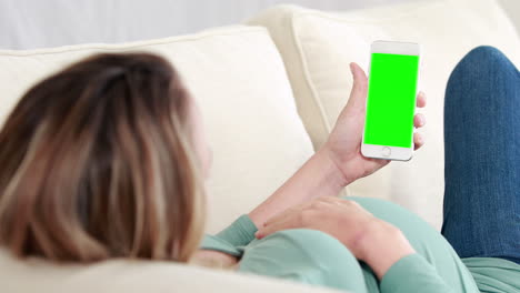 Pregnant-woman-laying-on-sofa-using-smartphone