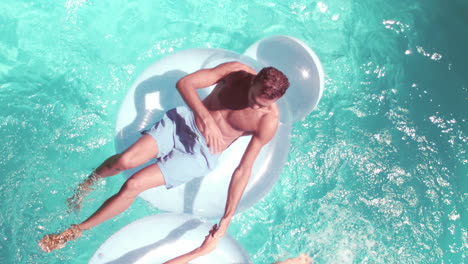 Attractive-couple-relaxing-on-lilos-in-pool