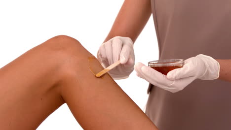 Therapist-waxing-womans-leg-at-spa-center