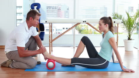Physiotherapist-using-foam-roller-with-patient