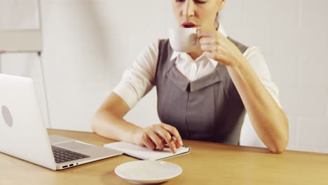 Ernsthafte-Geschäftsfrau-Macht-Sich-Notizen-Beim-Kaffeetrinken