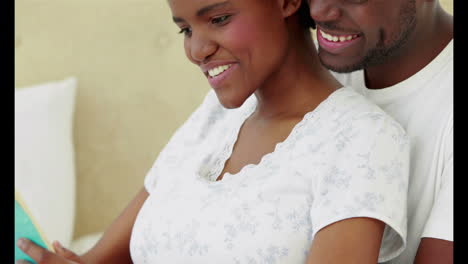 Happy-husband-with-pregnant-wife-reading-book