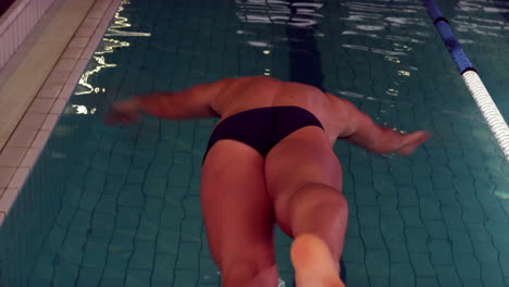 Rear-view-of-swimmer-diving-into-pool