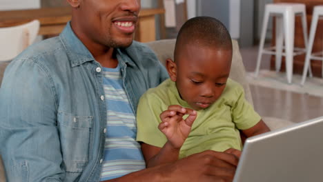Father-and-son-using-laptop-on-the-couch