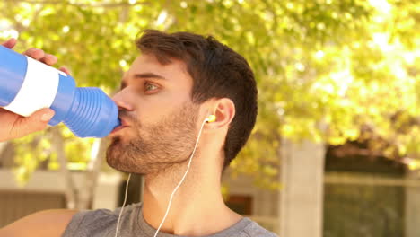 Un-Joven-Apuesto-Bebiendo-Agua-Durante-El-Jogging-