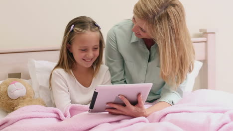 Mother-and-daughter-using-tablet-together-on-bed